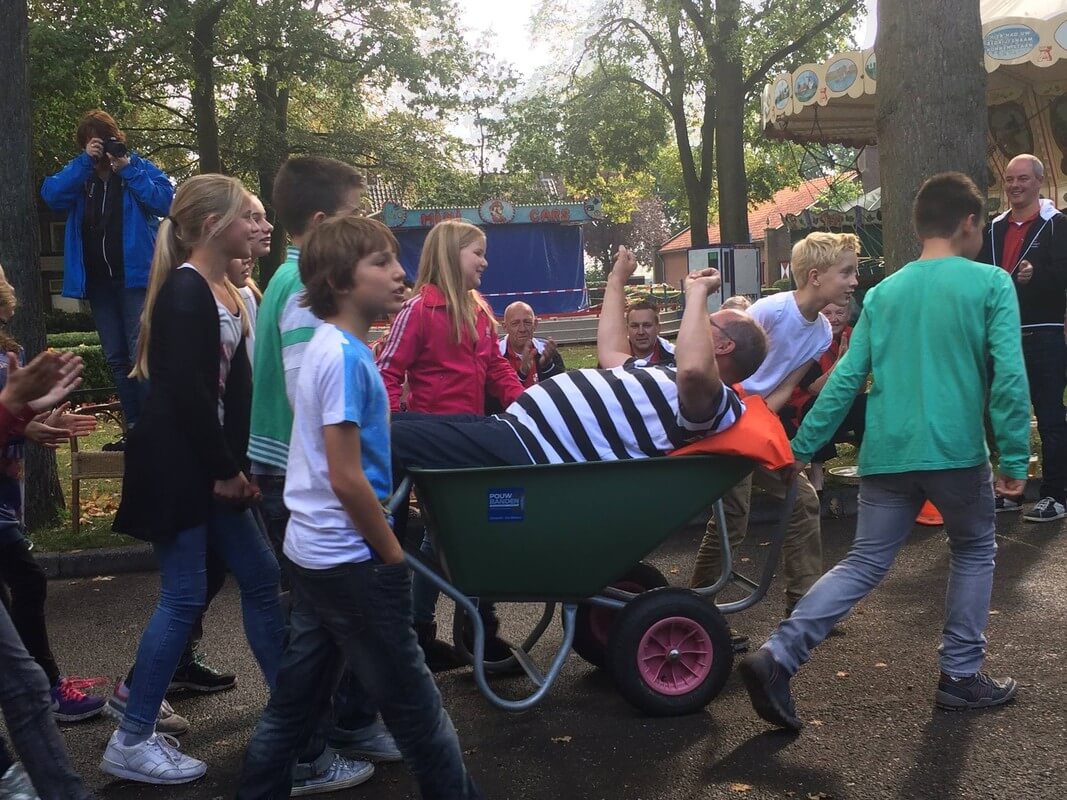 Meester Nico wordt in de kruiwagen rondgereden. Foto: X. van Asperen