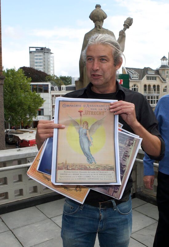 Rene de Kam en een poster van verzekeringsbedrijf De Utrecht. Foto: Ton van den Berg