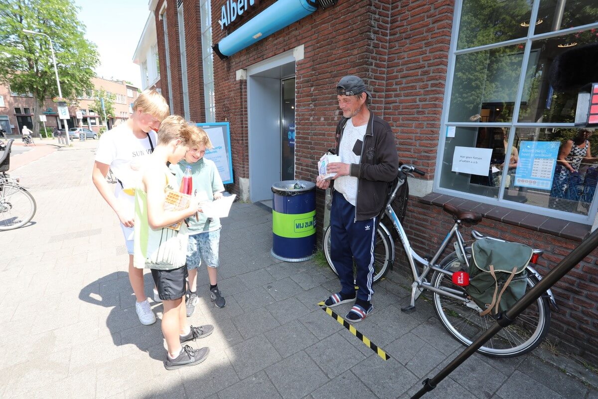 Straatnieuwsverkoper Eelco kijkt toe terwijl een groepje vrienden het net gekochte gedicht lezen. Foto: Ton van den Berg