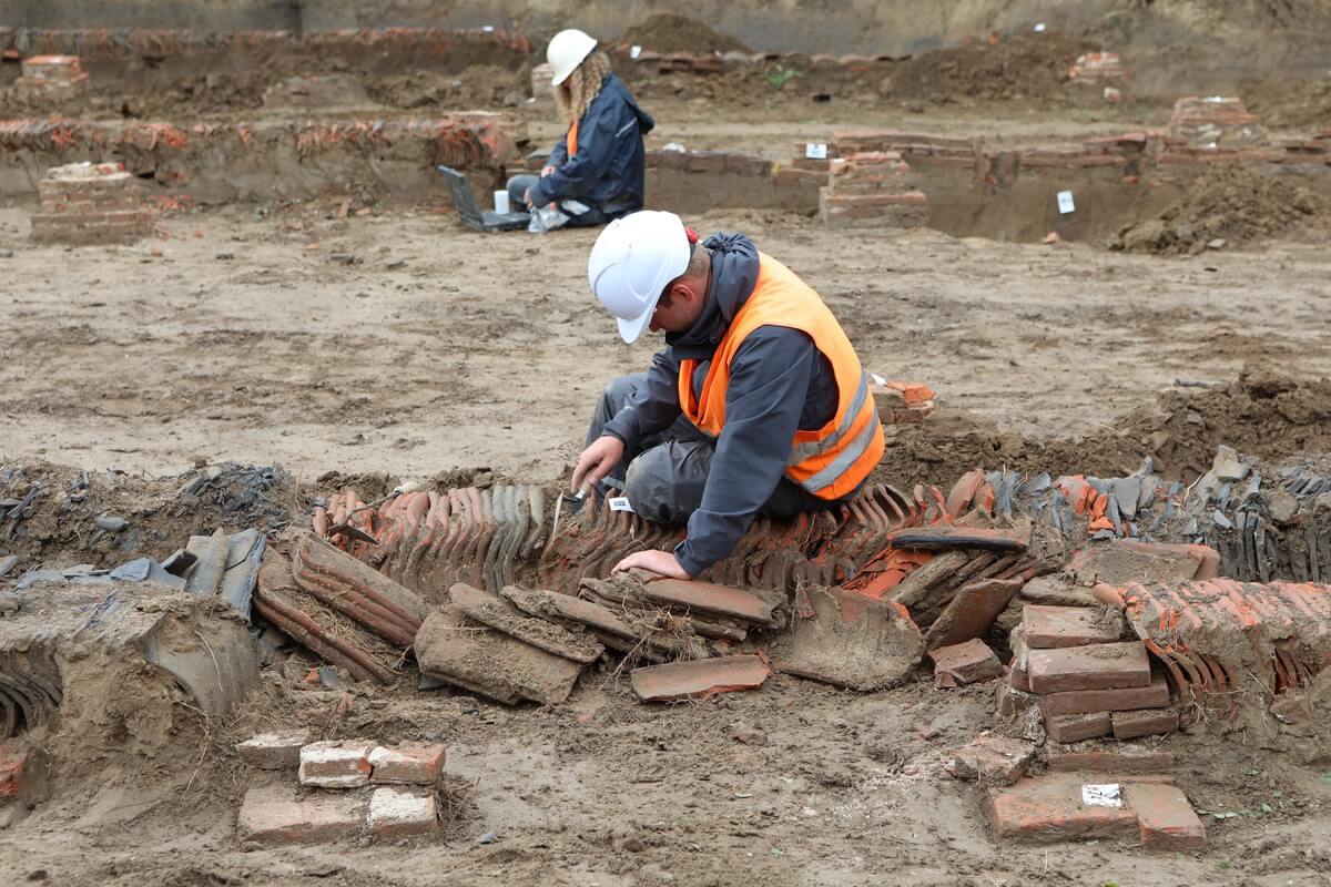 Archeologen aan het werk met de dakpannen.