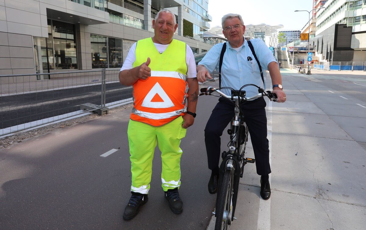 Fotograaf en verkeersregelaar Rob Sneltjes gebruikt zijn autoriteit om fietser Van Zanen even te laten stoppen.