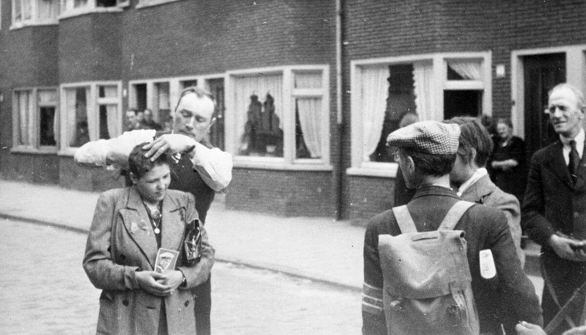 Een vrouw met in haar hand een foto van haar Duitse soldatenvriend wordt kaalgeknipt in de Morelstraat (Fruitbuurt). Foto: HUA